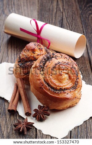 Buns with poppy seeds and roll paper tied with a red ribbon on wooden table