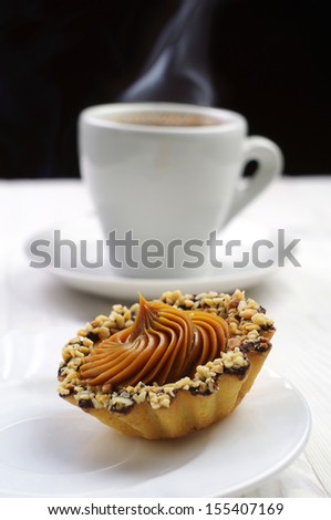 Cake with nuts and cup of hot coffee with shallow depth of field