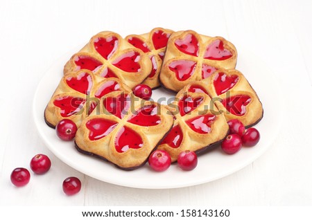 Sweet cookies with jam and cranberry on white table