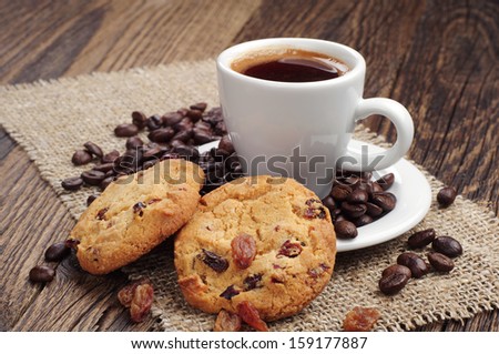 Cup of coffee and cookies with raisins and coffee beans on coarse fabric