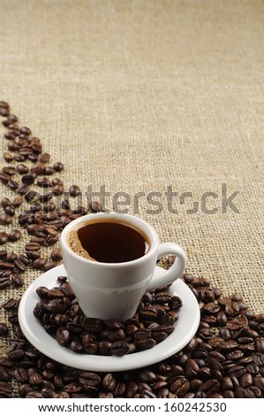 Background with cup of coffee and coffee beans on round fabric