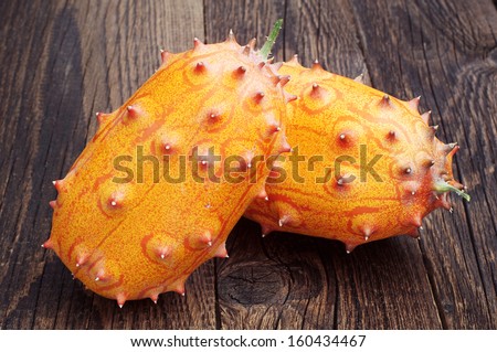 Two fruits Kiwano - African horned melon or cucumber on old wooden table