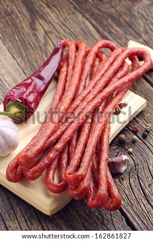 Thin dried sausages, pepper and garlic on old wooden table