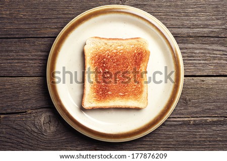 Toast bread in a brown plate on vintage wooden background. Top view