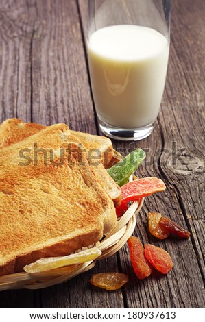 Glass of milk, toast bread and dried fruit on vintage wooden table