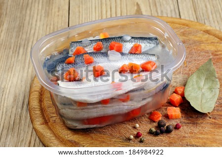 Marinated salted fish with carrots in opened jar on kitchen board