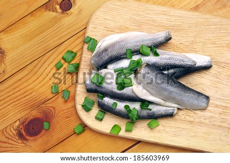 Marinated fish in a plate on a cutting board. Top view