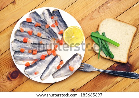Marinated salted fish in a plate on wooden table. Top view