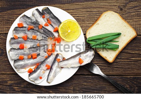 Marinated fish in a plate on vintage wooden table. Top view