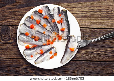 Marinated salted fish with carrots in a plate on wooden background
