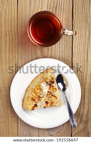 Top view of a cup of tea and slice pie with apples on wooden table