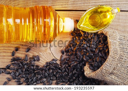 Vegetable oil and sunflower seeds in shack on wooden table. Top view