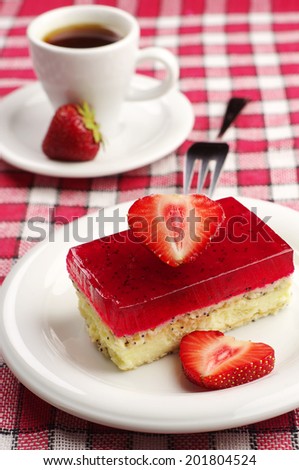 Tasty strawberry cake with poppy and cup of coffee on red tablecloth