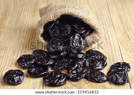 Dried plum in small sack on wooden table