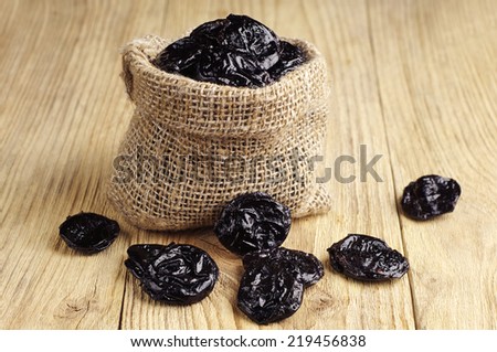 Dried plum in sack on wooden table
