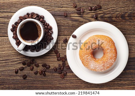 Donut with sugar and cup of hot coffee on old wooden table. Top view