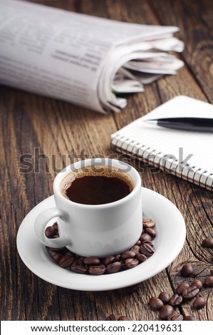 Coffee cup and newspaper on vintage wooden table