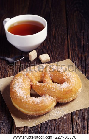 Pretzel with sugar and cup of hot tea on dark wooden table