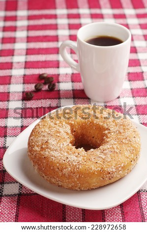 Breakfast with sweet donut and cup of black coffee on red tablecloth