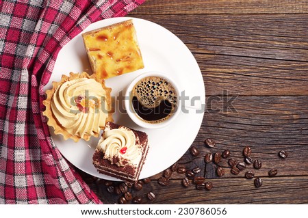 Sweet cakes and cup of hot coffee on dark wooden table. Top view