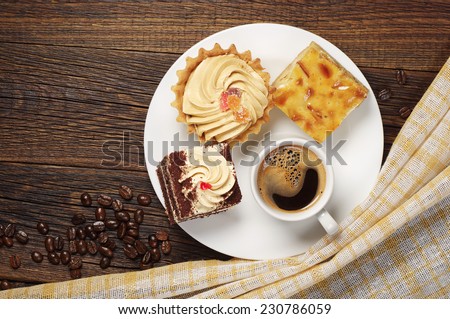 Tasty cakes and cup of hot coffee on old wooden table. Top view