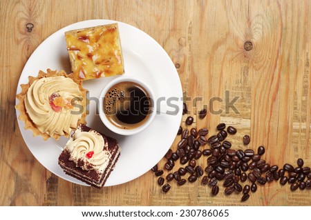 Plate with cakes and coffee cup on old wooden table. Top view