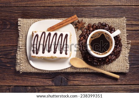 Cup of hot coffee and creamy cake with chocolate on old wooden table, top view