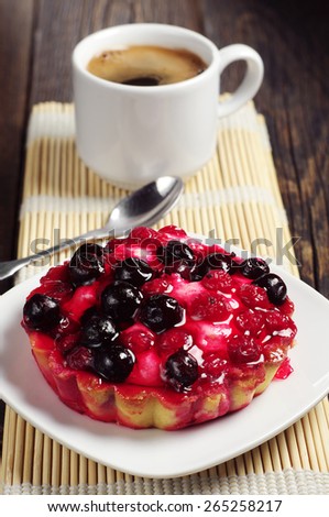 Cake with berries in plate and coffee cup on bamboo napkin