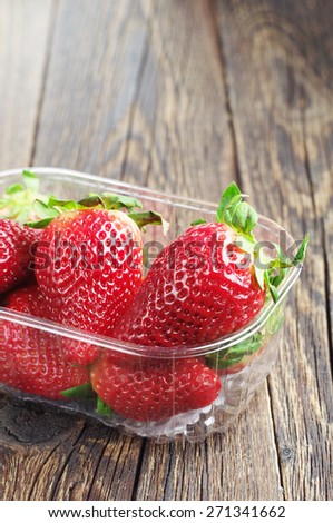 Ripe strawberries in packing on old wooden table