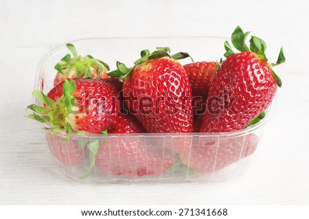 Fresh strawberries in plastic packing on old white table
