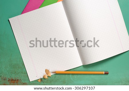 Opened exercise books and pencils on the desk, top view