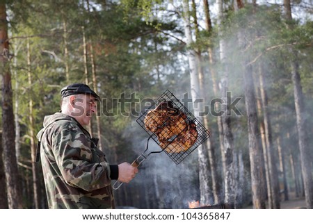 Portrait of man with meat grill in a forest