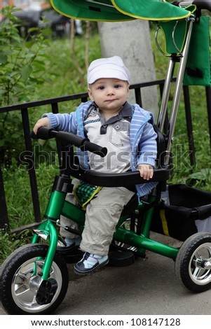 Funny child is on tricycle in a summer park