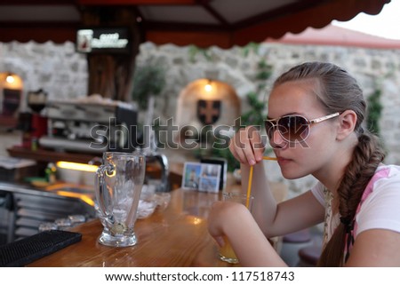 Girl is drinking juice at bar in the evening