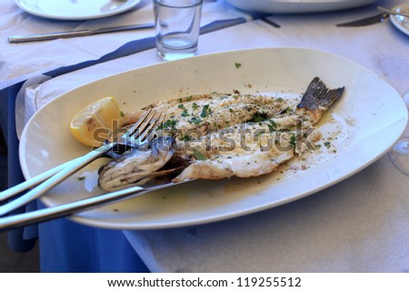 Cooked fish on a white plate in a seafood restaurant