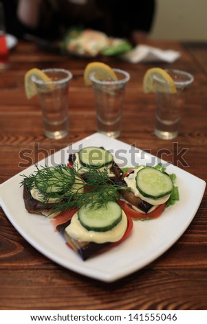 Plate of vegetables and glasses of tequila on a wooden table