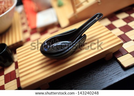 Black spoon on a wooden board in an asian restaurant