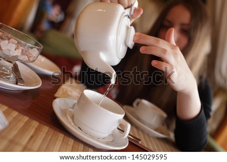 Teen fills cup of tea in the restaurant