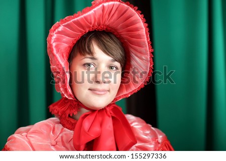 Young woman is posing in a red historical clothing