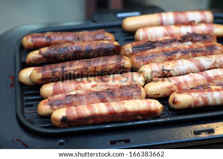 Grilling bacon wrapped sausages on an electric grill