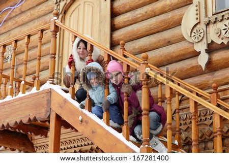Family sitting on the stairs of a wooden house in winter