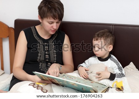 Mother reading book for her son in the bed