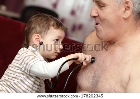 Kid examines his grandfather using stethoscope at home