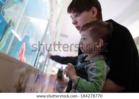 Mom tells her son about fish at an oceanarium