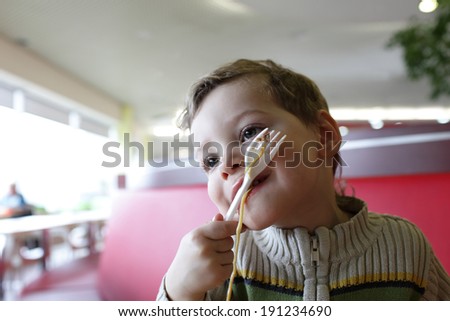 Kid eating noodles at the asian restaurant