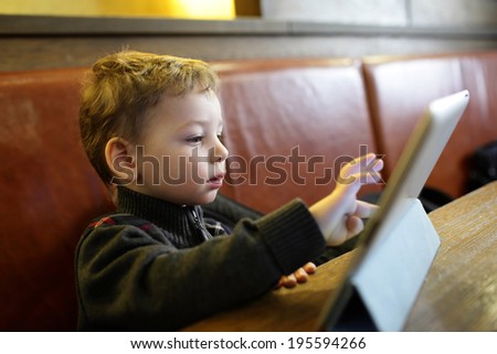 Kid playing on a Tablet PC in the restaurant