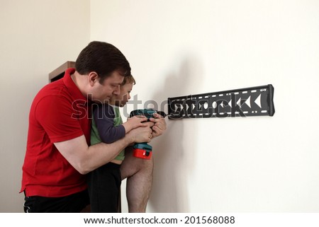 Family installing mount TV on the wall at home