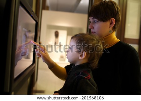 Mother and her son using touch screen in a museum