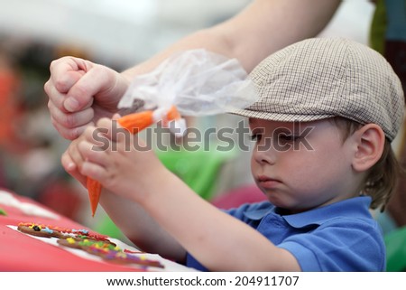 Child painting gingerbread shapes with a food coloring