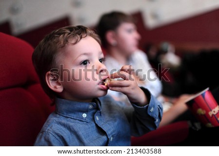 The child has popcorn in the cinema